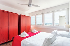 Een hotelkamer met een bed, een rode garderobe en een raam met uitzicht op zee.