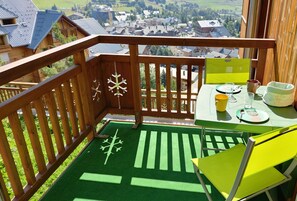 A balcony with a view of a town, a table with a chair, and a snowflake decoration. - Studio with balcony and ski slopes view (Les Deux Alpes)