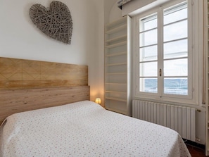 Ein Schlafzimmer mit einem Bett, einem Wandbild, einem Fenster mit Meerblick und einer Heizung.