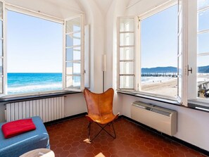 Ein Zimmer mit Blick auf den Strand, ein Stuhl, ein rotes Handtuch und ein Heizkörper.