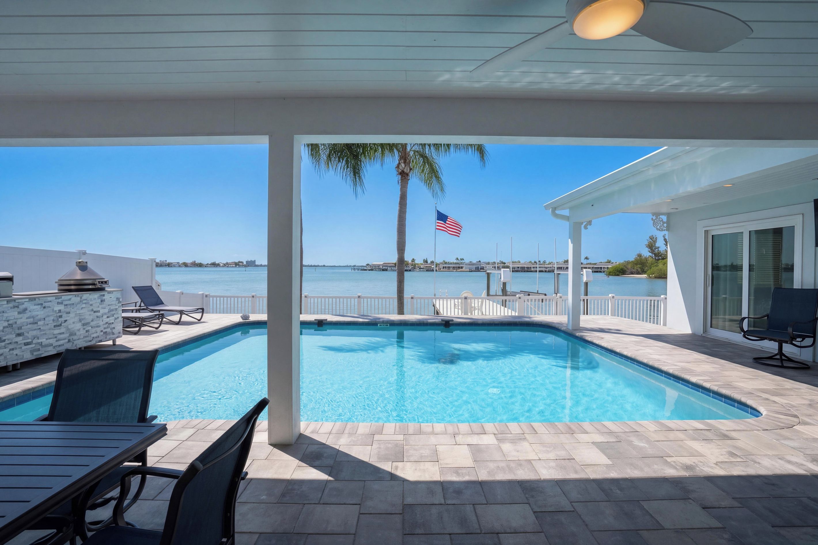 A pool with a view of the sea, a flag, and a palm tree.