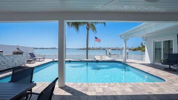 A pool with a view of the sea, a flag, and a palm tree.