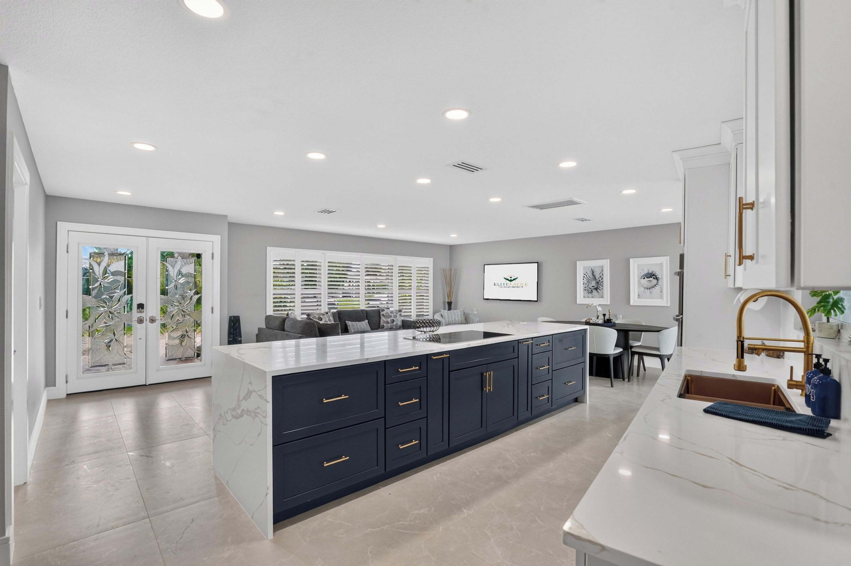 A modern kitchen with a large island, dark cabinetry, and a white countertop.