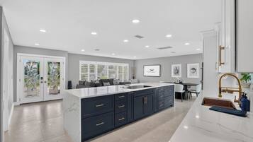 A modern kitchen with a large island, dark cabinetry, and a white countertop.