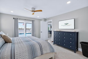A bedroom with a bed, a ceiling fan, a dresser, and a view of a pool. - Waterfront Getaway Pool, Boat Dock & Kayaks (St. Petersburg)