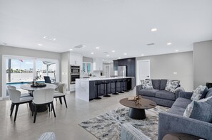 A modern living space with a dining area, a kitchen, and a seating area with a view. - Waterfront Getaway Pool, Boat Dock & Kayaks (St. Petersburg)