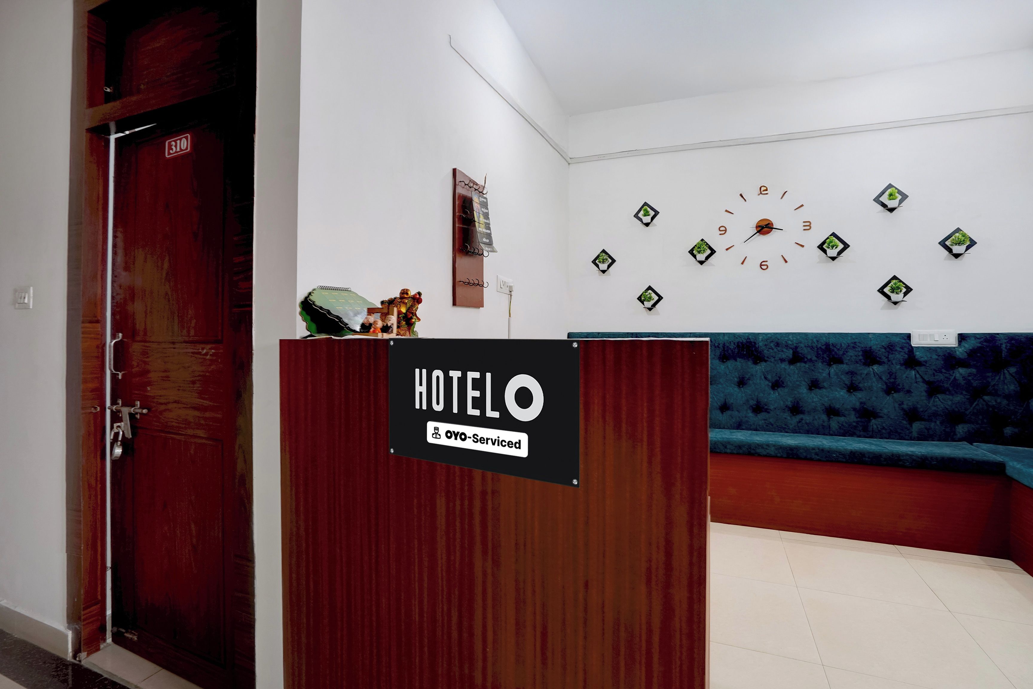 A hotel reception area with a wooden reception desk, a clock on the wall, and a blue sofa.