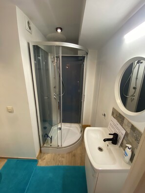 A bathroom with a glass-enclosed shower, a white sink, and a mirror. - Studio with air conditioning and bike storage (Huy)