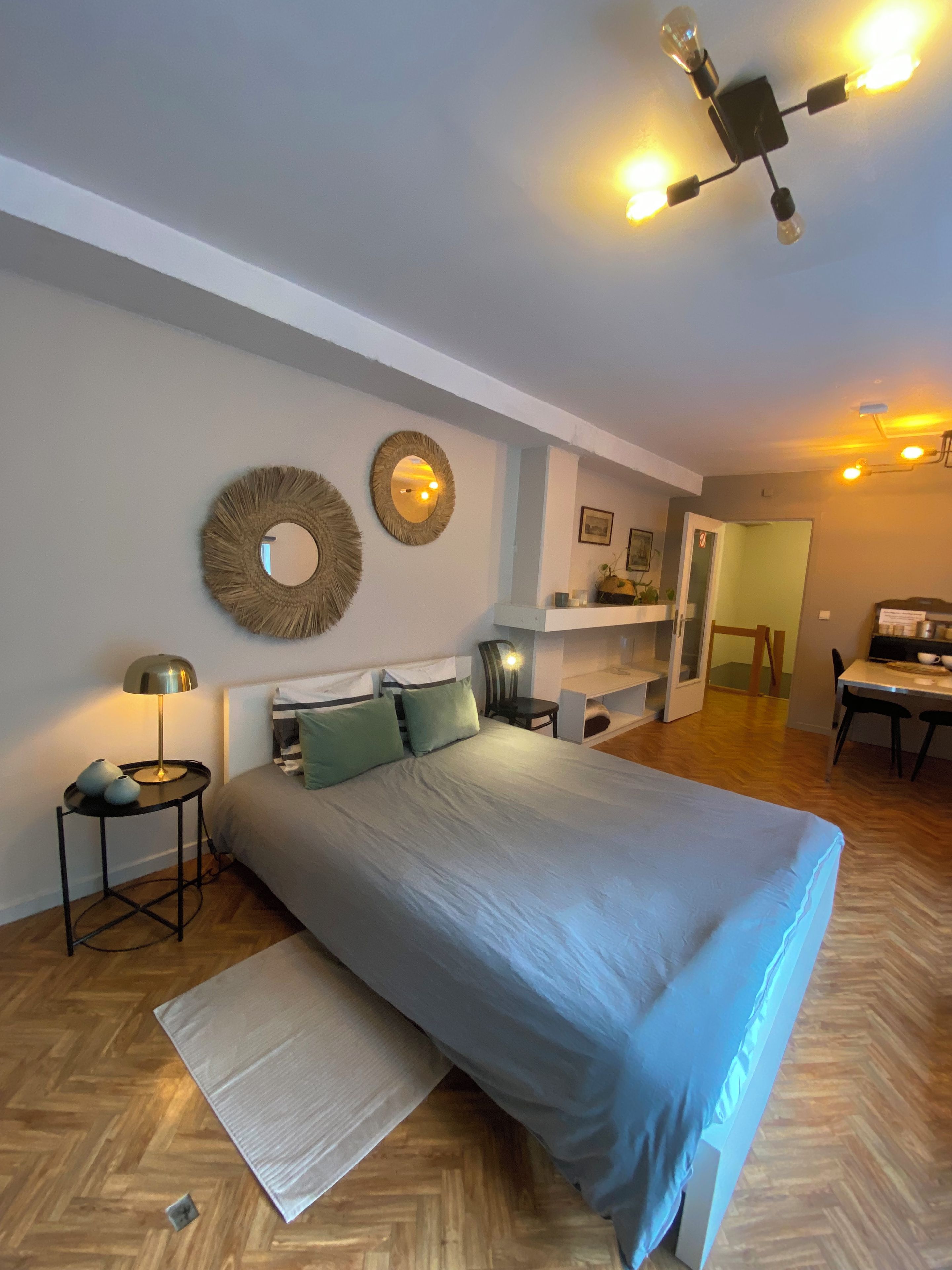 Een slaapkamer met een groot bed, nachtkastjes, een bureau en een plafondlamp.