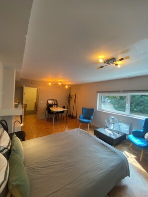 A bedroom with a bed, a desk, two chairs, a fan, and a window with a view. - Studio with air conditioning and bike storage (Huy)