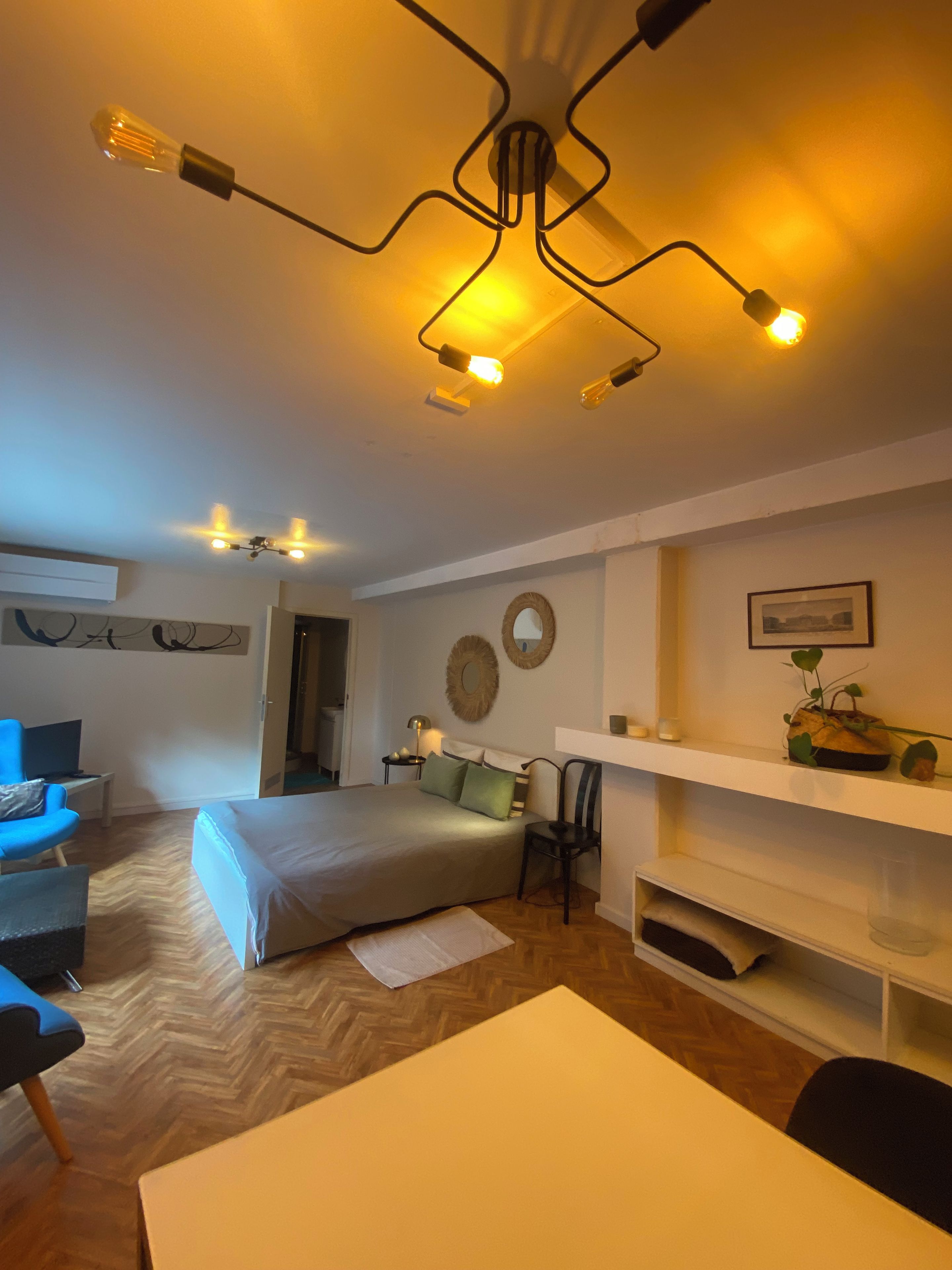Una camera d'albergo con un letto, una scrivania, una sedia, una lampada e una luce a soffitto.