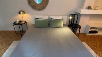 Een slaapkamer met een groot bed, twee spiegelwanden, een bedlampje en een klein nachtkastje.