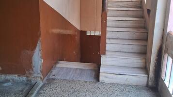 Una escalera que lleva a un rellano con suelo de baldosas y una puerta.