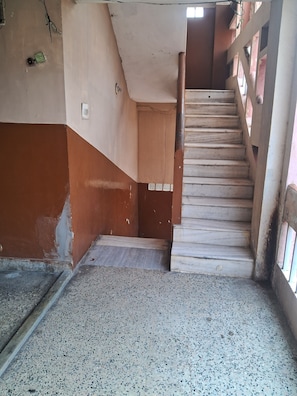 A staircase leading to a landing with a tiled floor and a door. - Hotel Swamy Lodge  (Vijayawada)