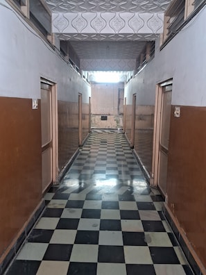Un pasillo con piso a cuadros, puertas a ambos lados y un techo con diseño.