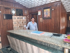 A reception desk with a clock, framed pictures, and a calendar on the wall. - Hotel Swamy Lodge  (Vijayawada)