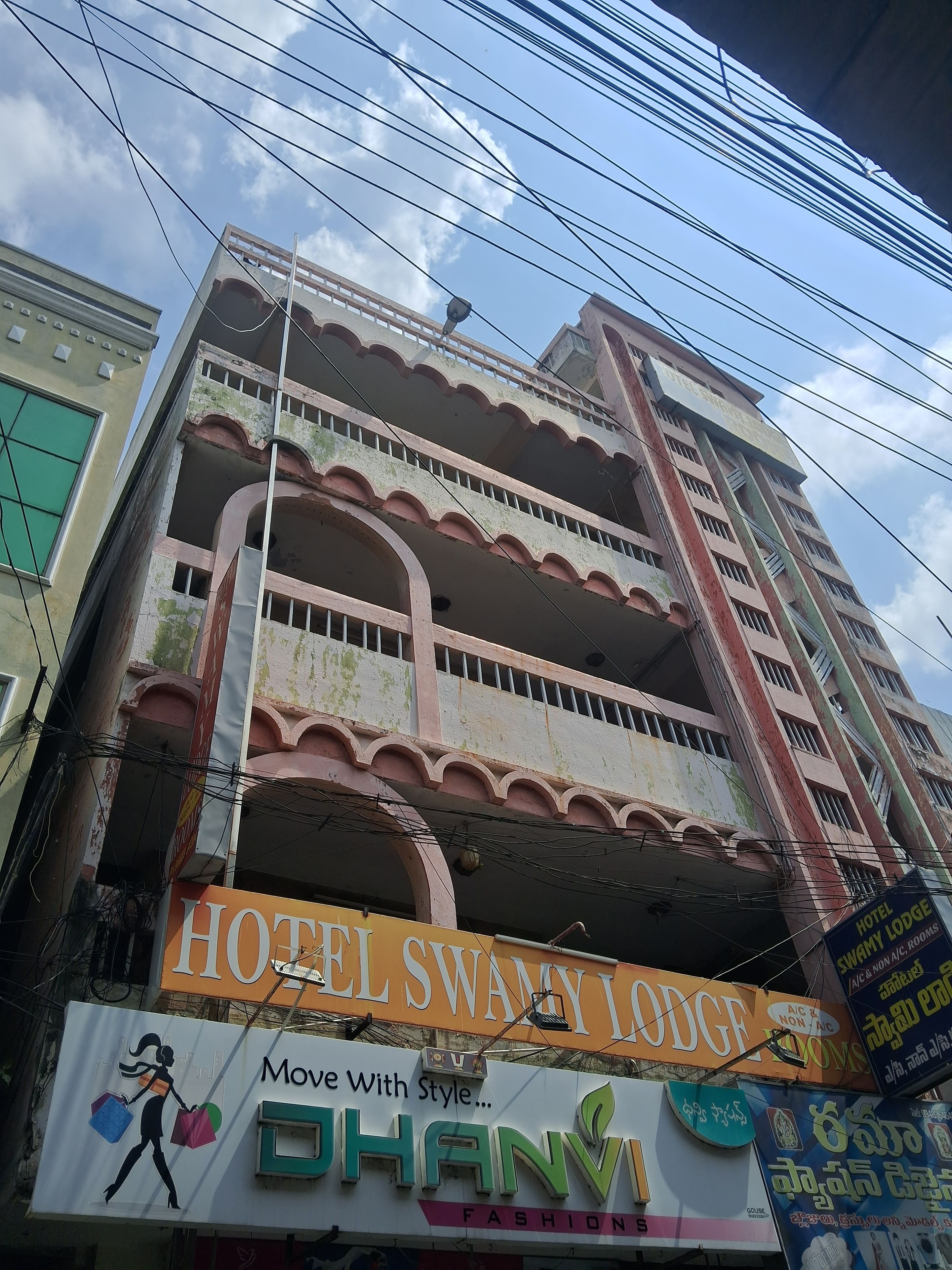 A multi-story building with a sign for Hotel Swamy Lodge and a fashion store named DHANI.