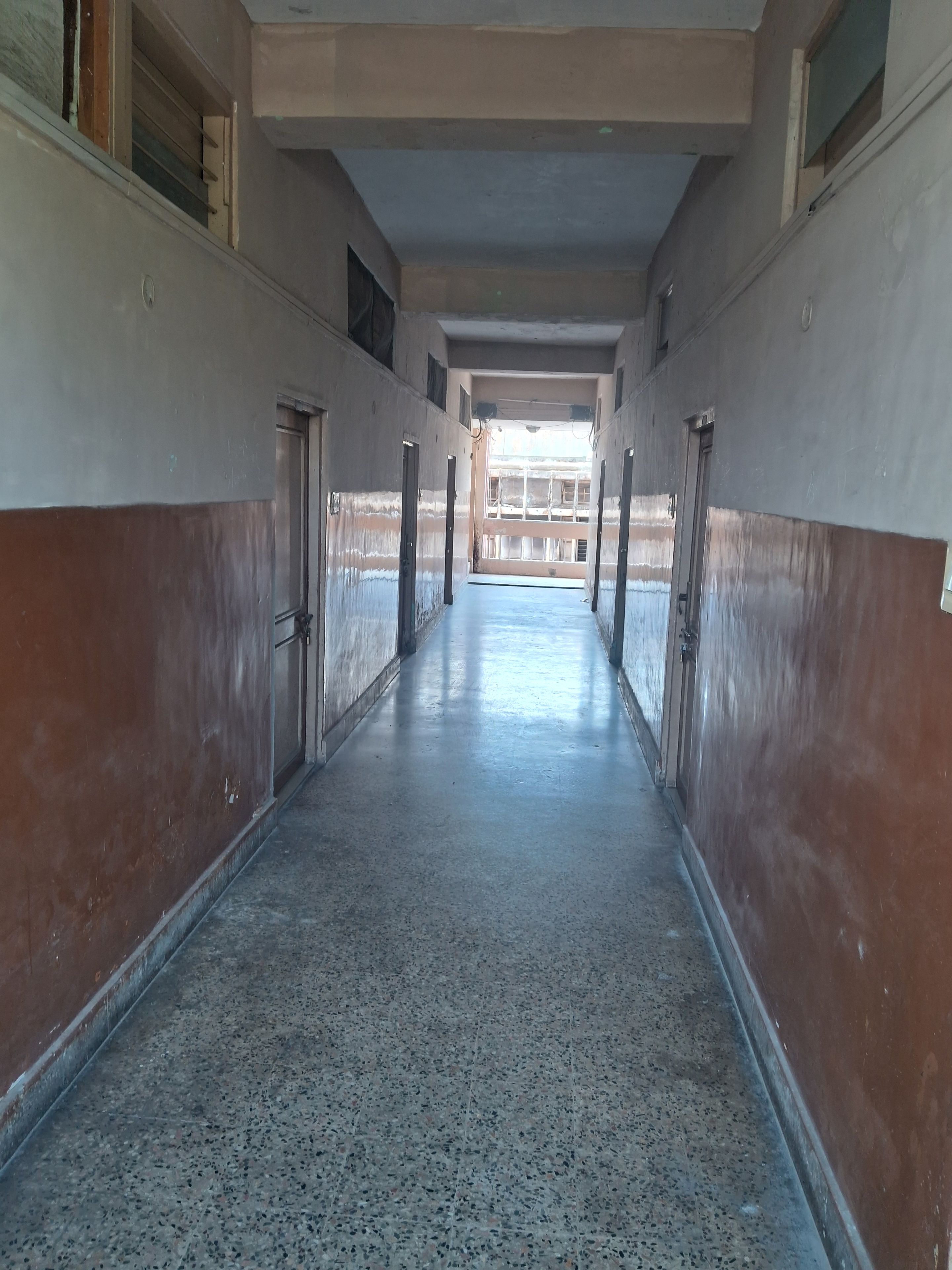 Passadís amb portes a ambdós costats que condueix a una zona oberta amb vista a un edifici.
