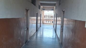 A corridor with doors on both sides, leading to an open area with a view of a building.