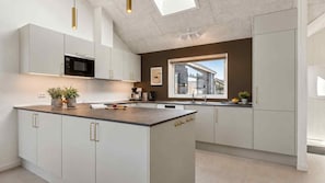 A modern kitchen with white cabinetry, a central island, and pendant lighting. - VillaVilla 997 - Odsherred, Nordsjælland (Højby)