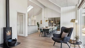 A modern interior with a wood-burning stove, dining area, and a cozy seating area with a lamp. - VillaVilla 997 - Odsherred, Nordsjælland (Højby)