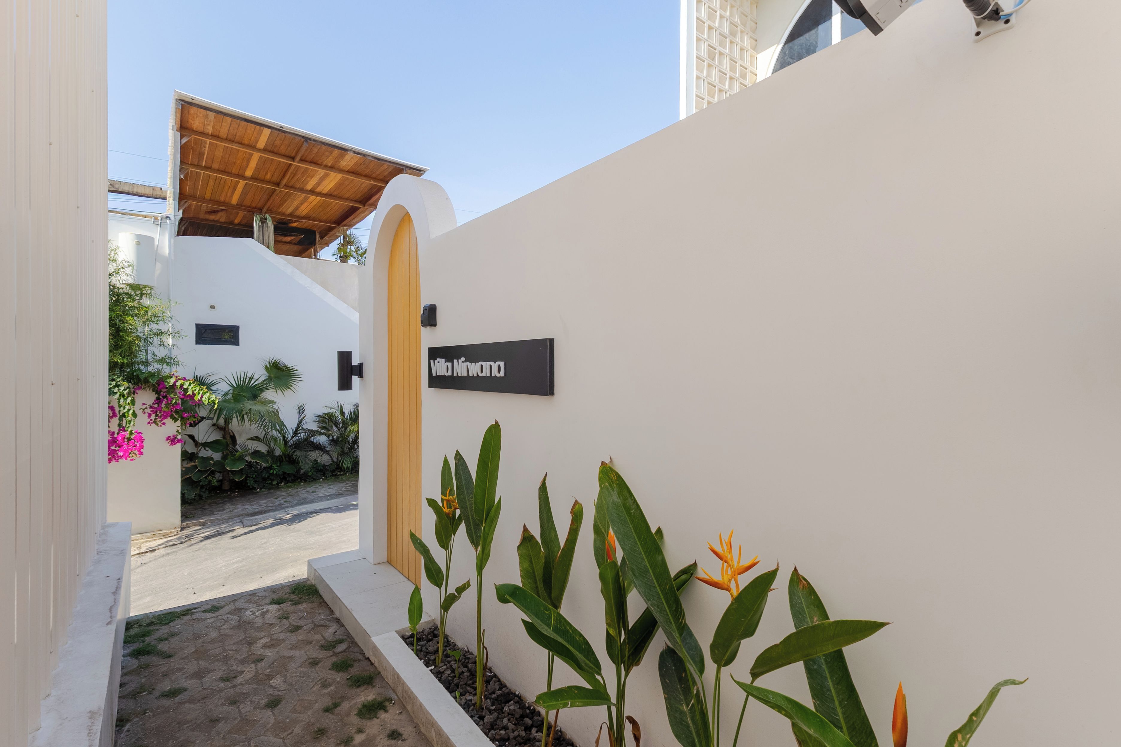 Un bâtiment blanc avec une enseigne indiquant « Villa Nirvana » et une entrée abritée.
