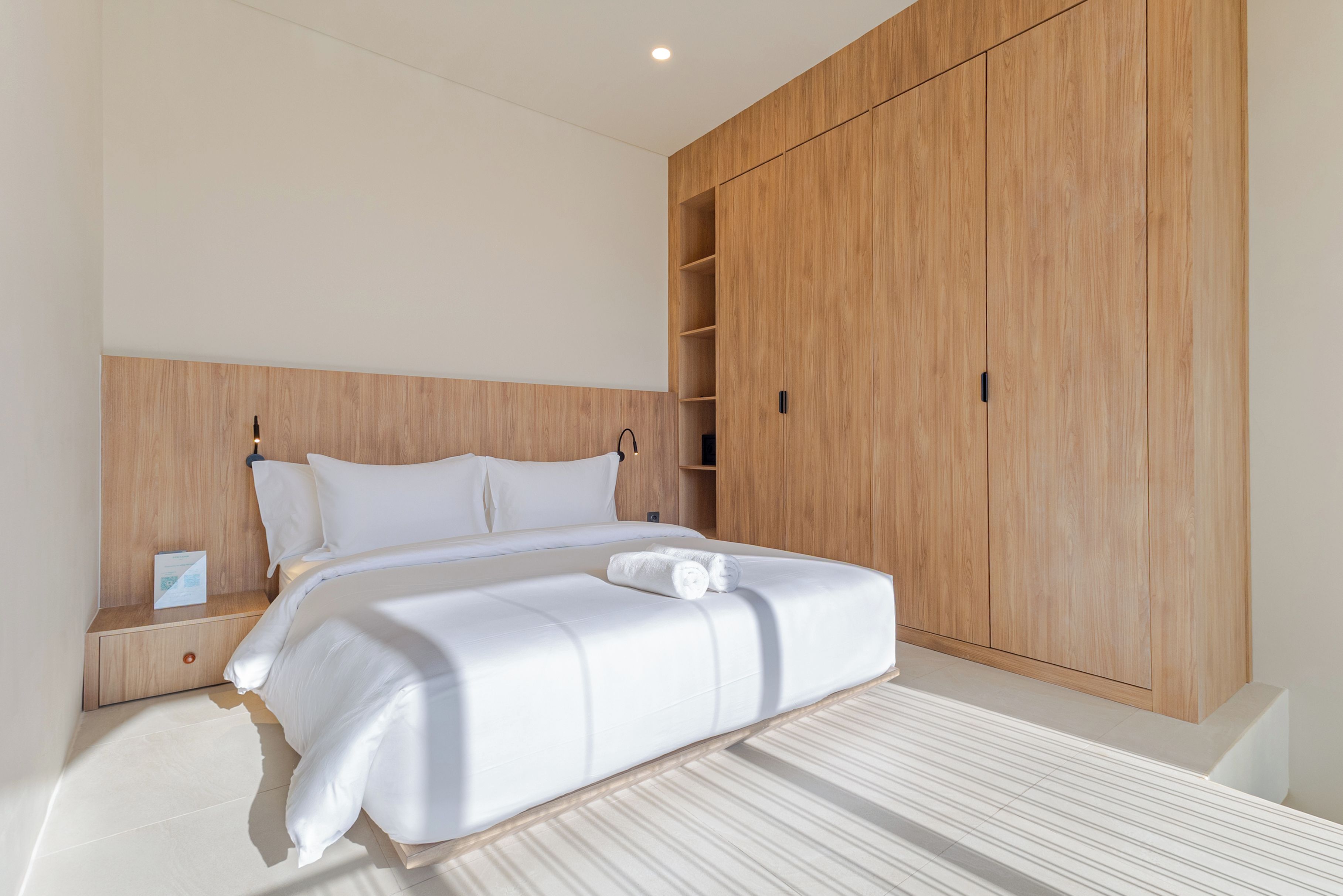 Une chambre d’hôtel avec un grand lit, une armoire en bois et une table de chevet.