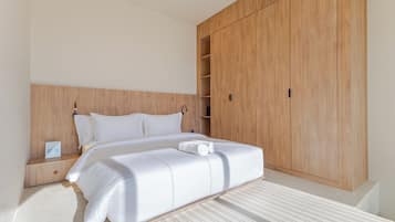 A hotel room with a large bed, wooden wardrobe, and a nightstand.