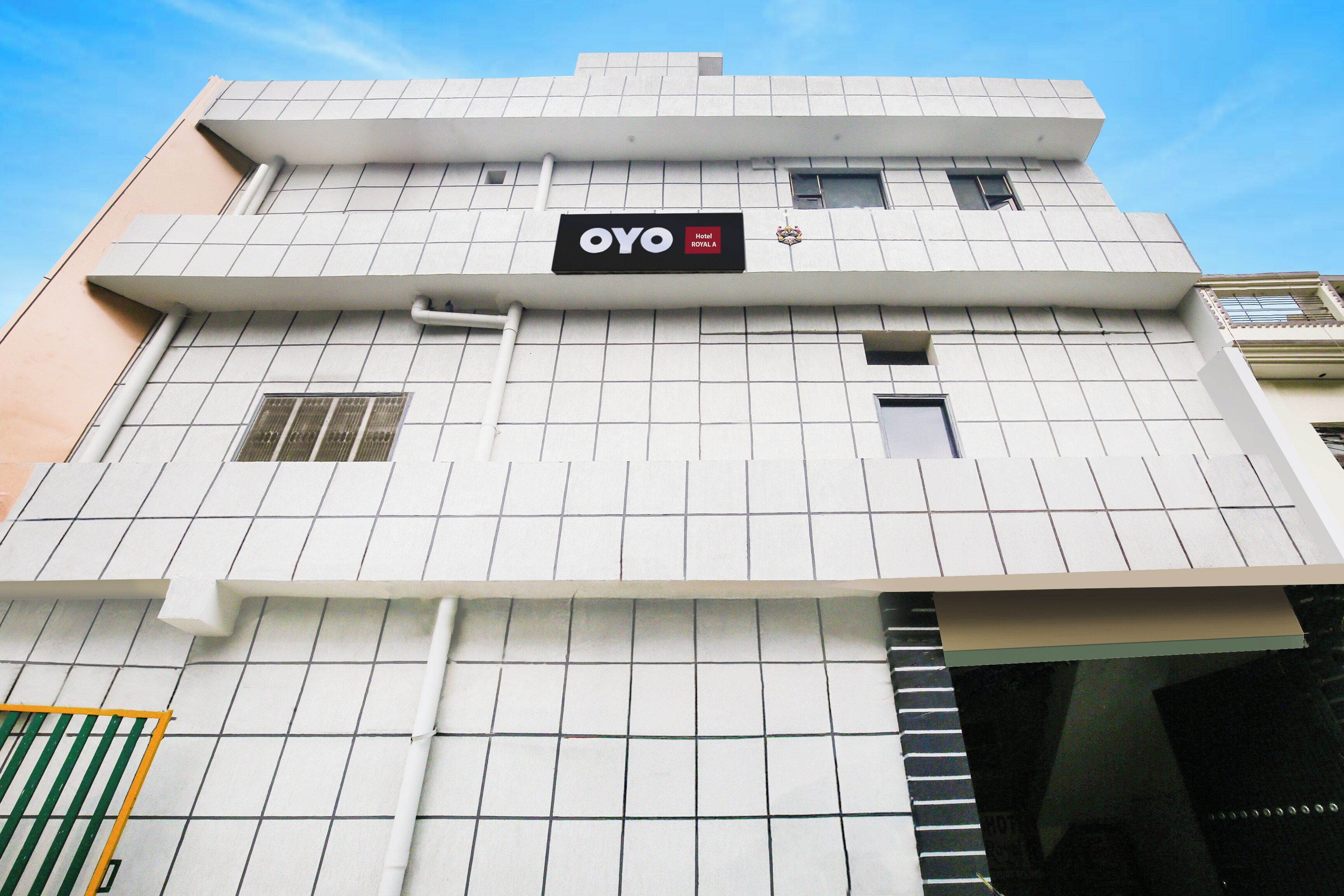 A hotel building with a tiled facade, a sign reading 'OYO Hotel Royal A', and a small window with a balcony.