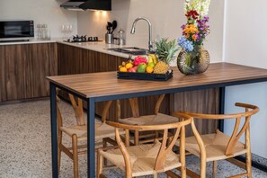 Una cocina moderna con una mesa de madera, dos sillas de mimbre, una cesta de frutas y un florero con flores.