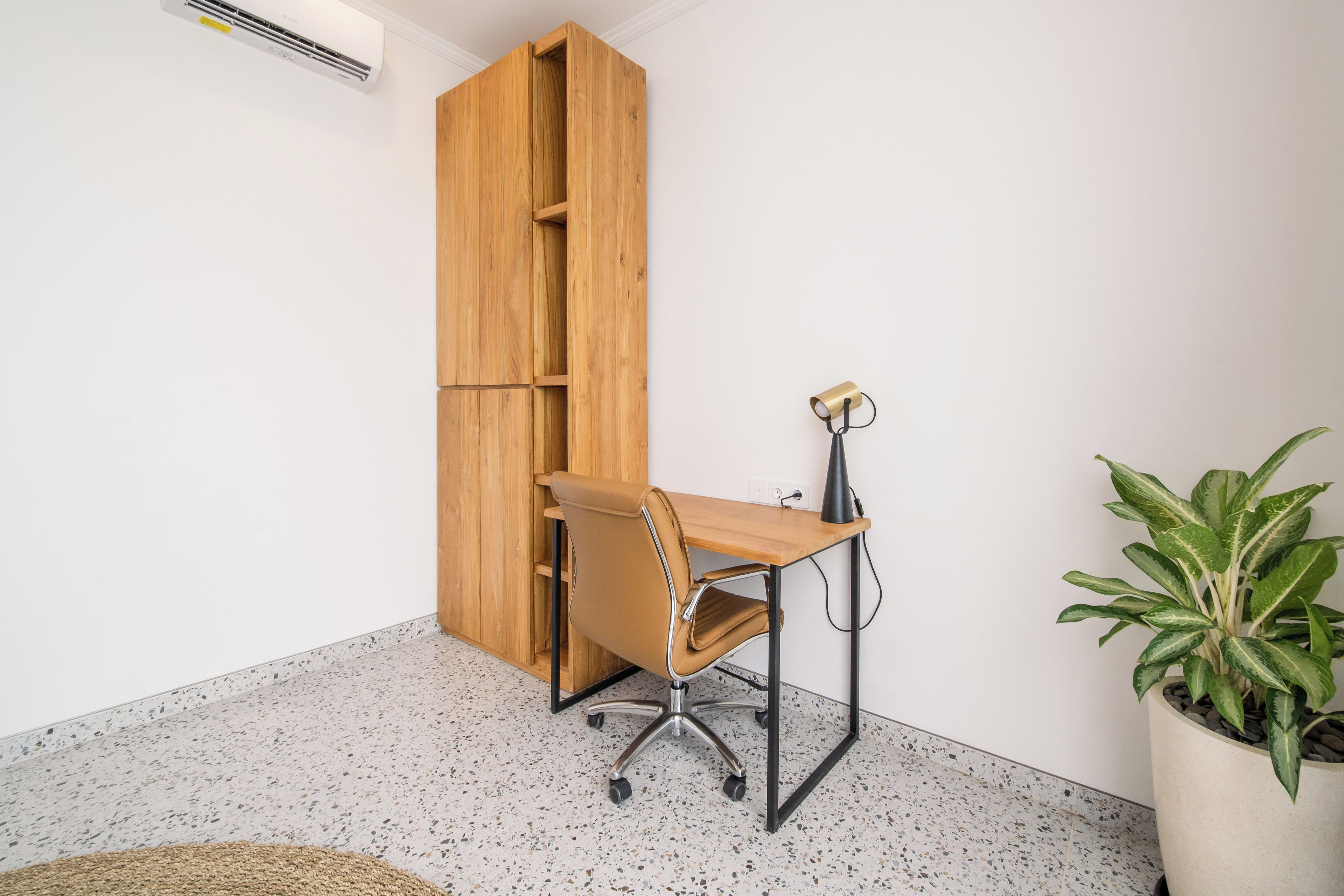 Un espacio de trabajo con un escritorio de madera, una silla, una lámpara y una planta en maceta.