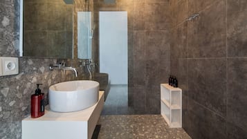 Un baño moderno con lavamanos blanco, un espejo grande y zona de ducha.