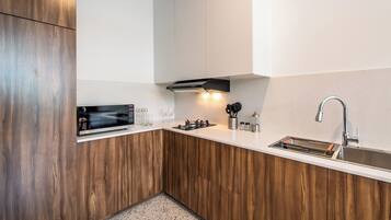 Una cocina moderna con armarios de madera, un microondas integrado y un lavamanos de acero inoxidable.