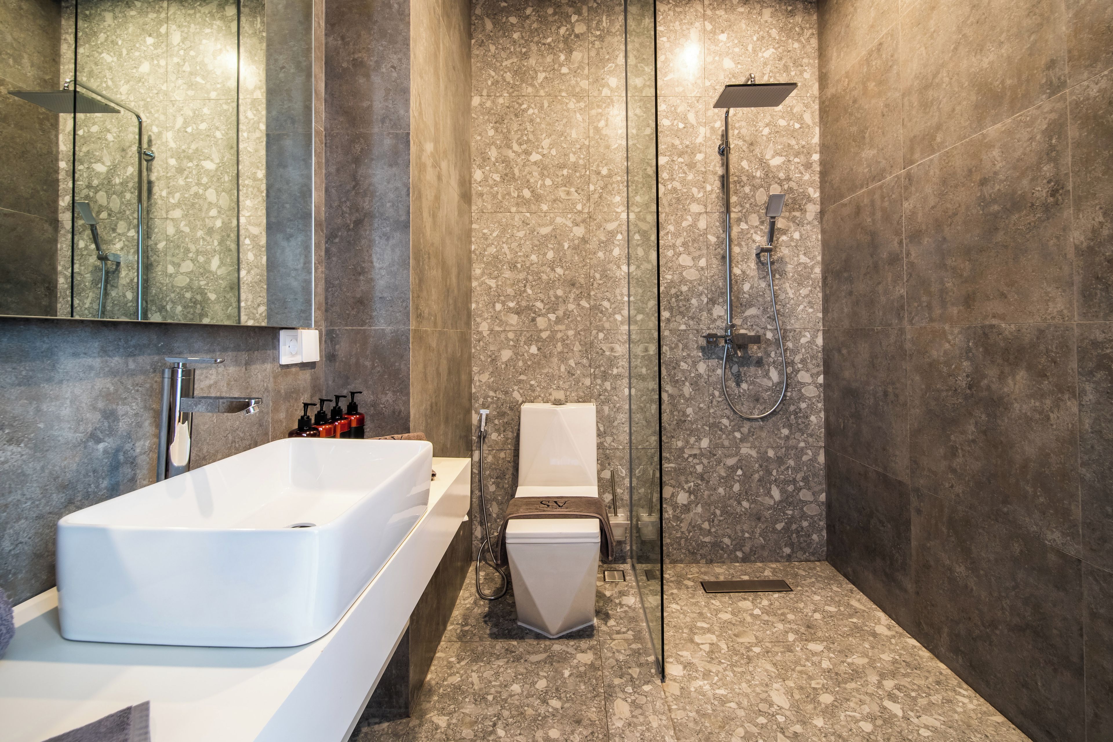 A modern bathroom with a large rectangular sink, a toilet, and a shower area.