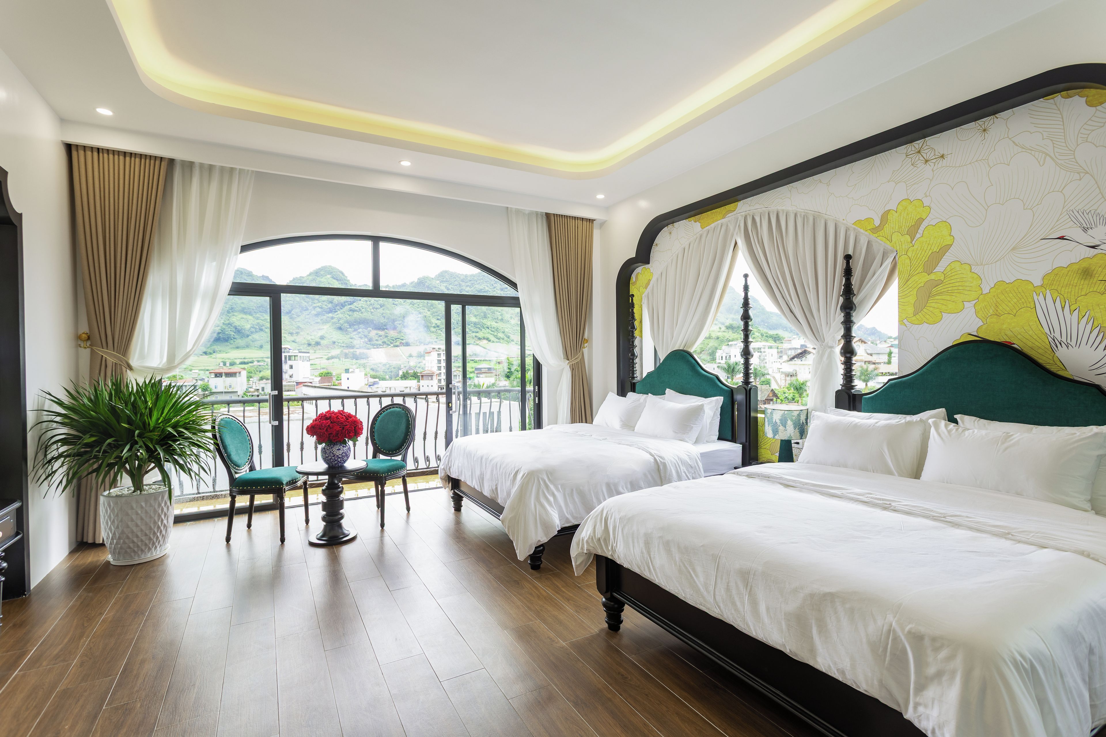 A hotel room with two beds, a balcony, a view of the city, and a large window.