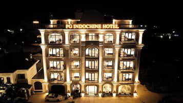 Een meerhoog hotel met verlichte signage met de tekst 'PG INDOCHINE HOTEL' bovenaan.
