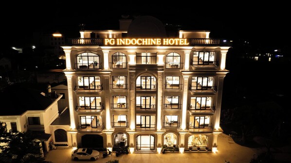 A multi-story hotel with illuminated signage reading 'PG INDOCHINE HOTEL' at the top.