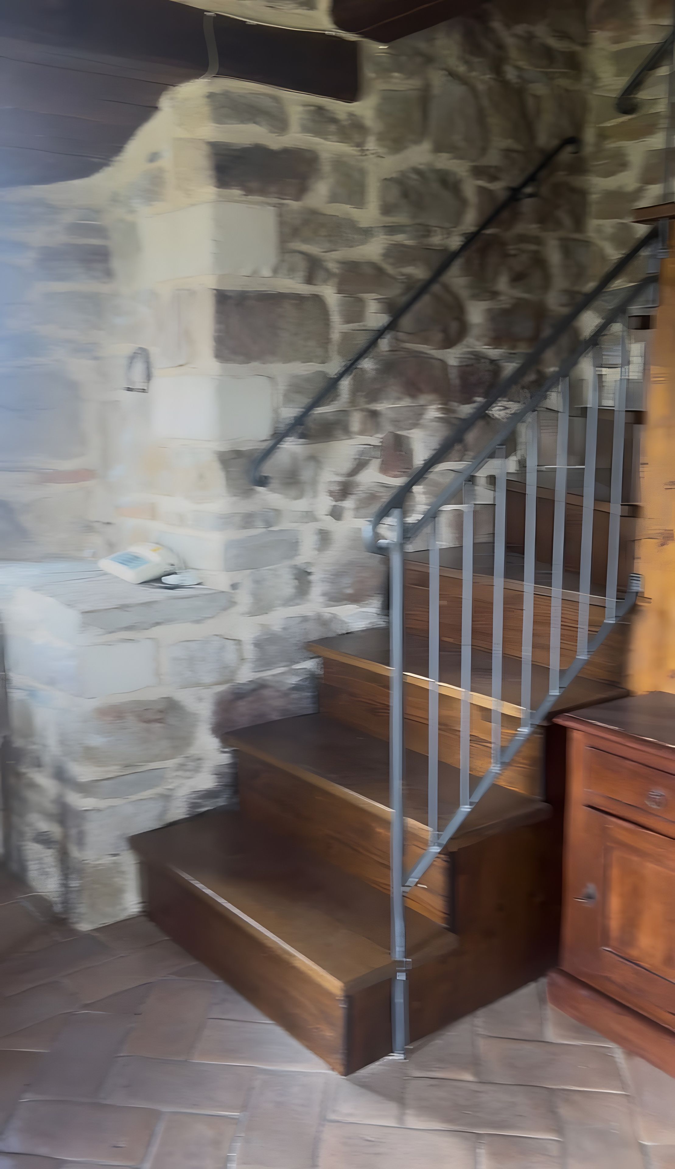 Eine Treppe mit Steinwänden, Holzstufen und Metallgeländern.