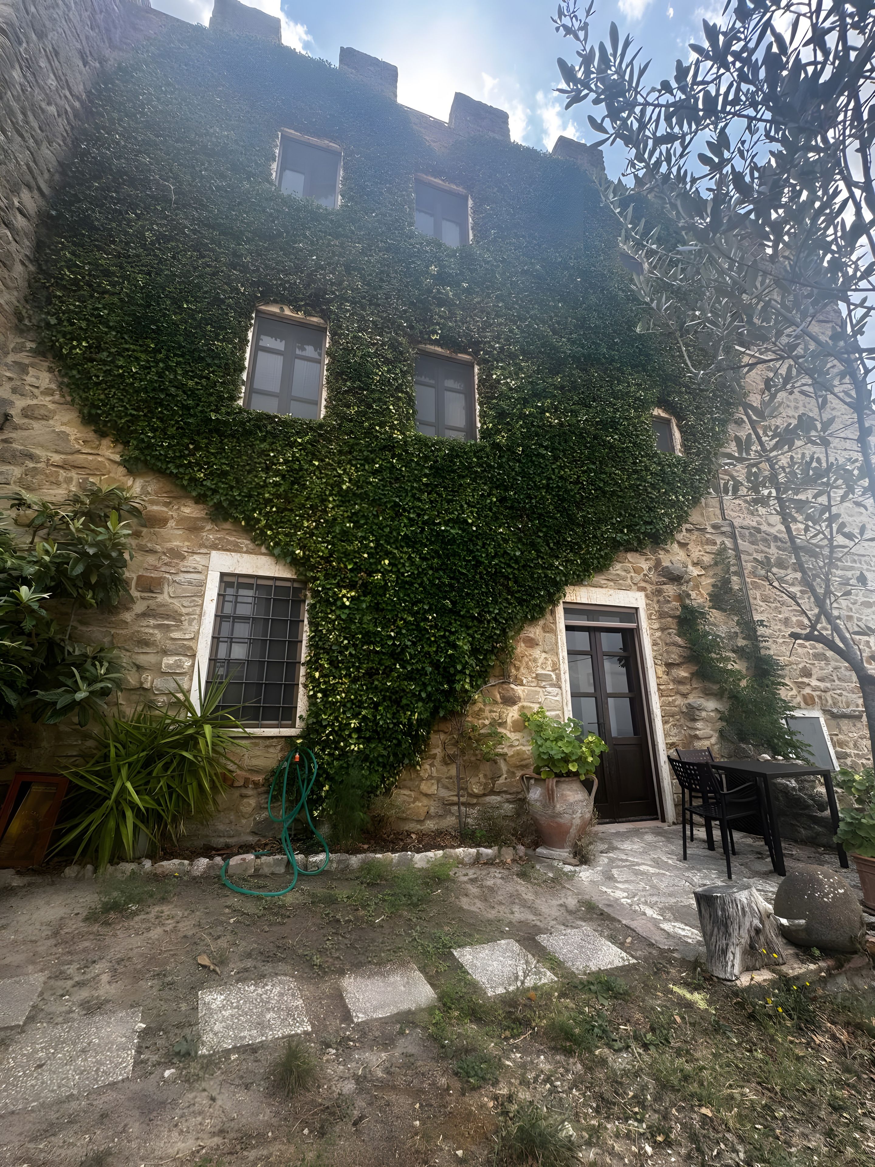 Un edificio in pietra con muri ricoperti d'edera, una porta e finestre.