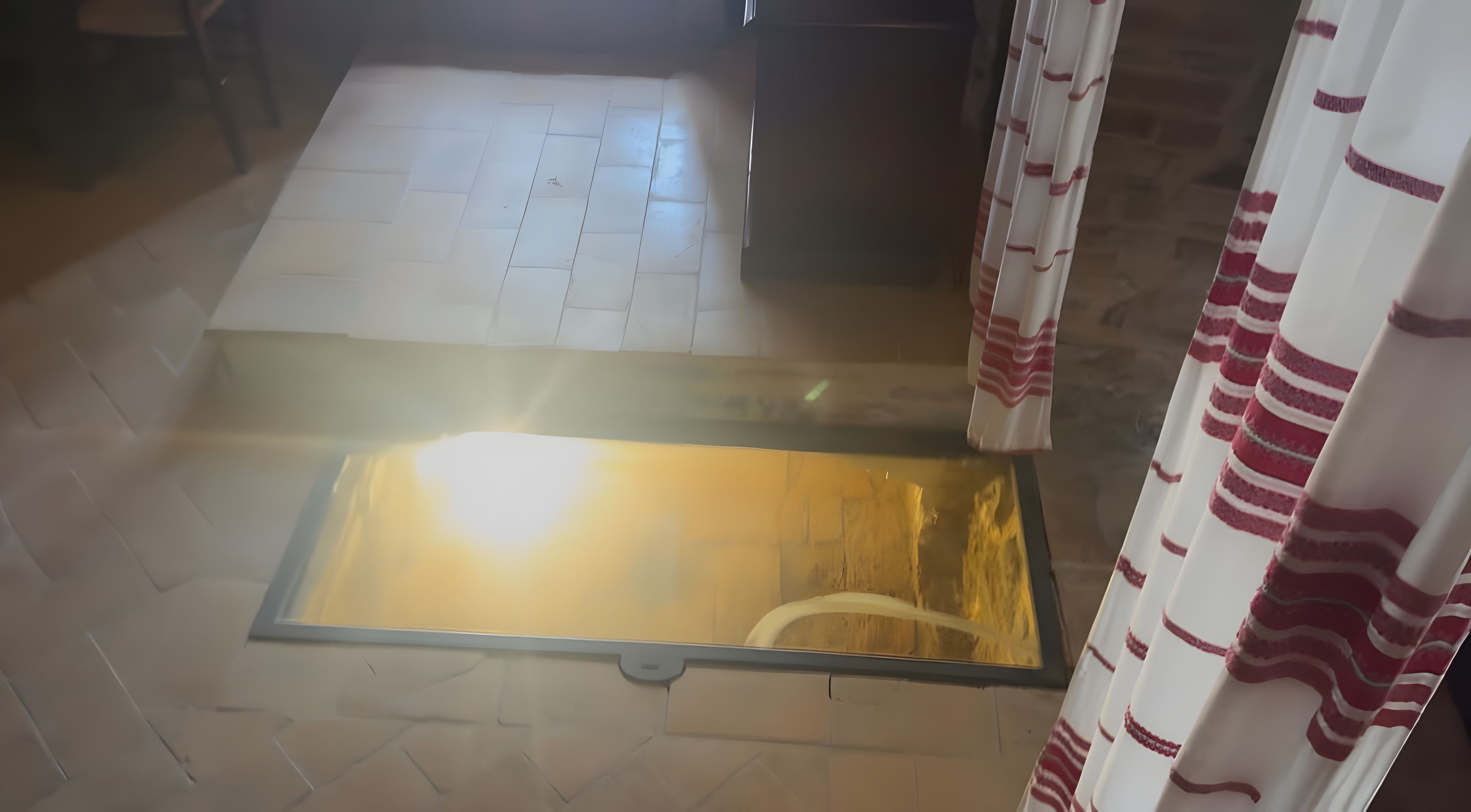 Una stanza con pavimento piastrellato, una finestra vista e una tenda a righe.