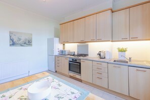Eine moderne Küche mit Holdekor, einem Gaskochfeld, einem Kühlschrank und einer Spüle.