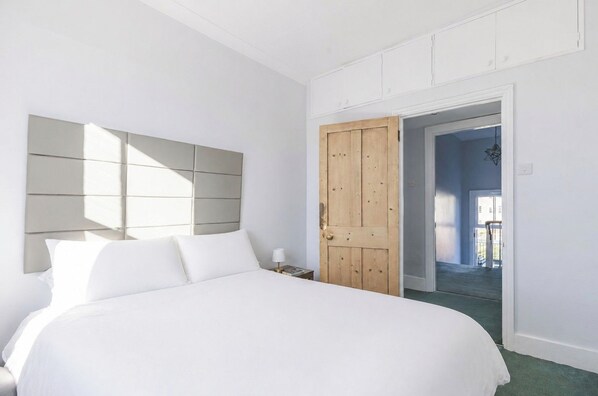 Ein Schlafzimmer mit einem großen Bett, einer Holztür und Blick ins Freie.