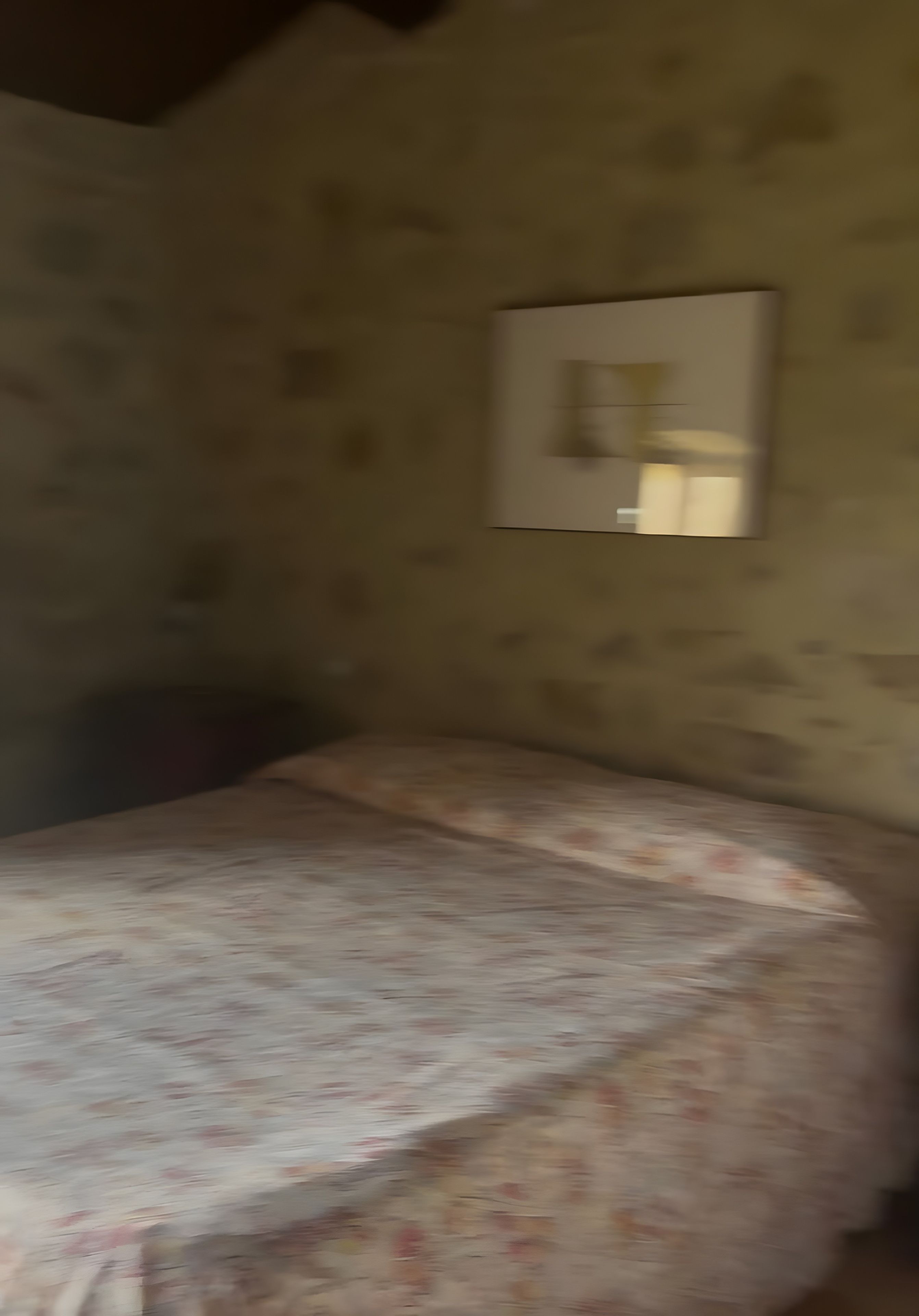 A room with a bed, a wall-mounted light, and a textured wall.