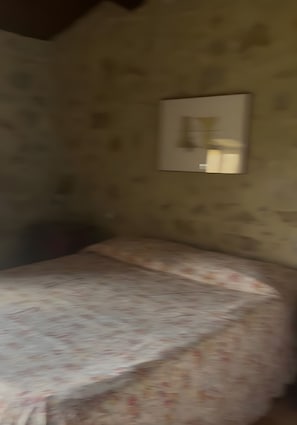 Ein Zimmer mit einem Bett, einer Wandleuchte und einer Wand mit Struktur.
