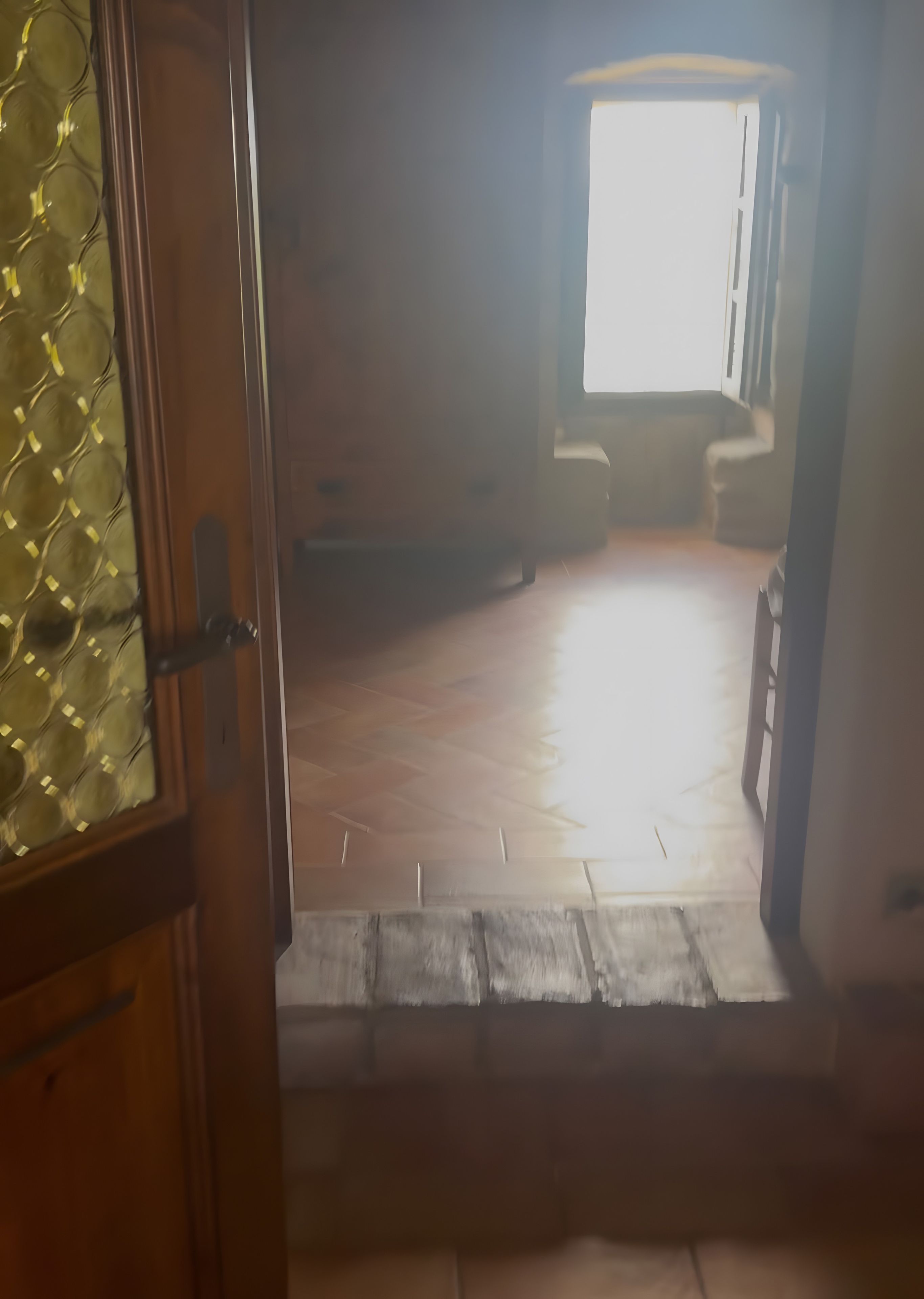 Un espacio interior con piso de madera, una ventana y una puerta.