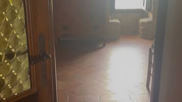 Un espacio interior con piso de madera, una ventana y una puerta.