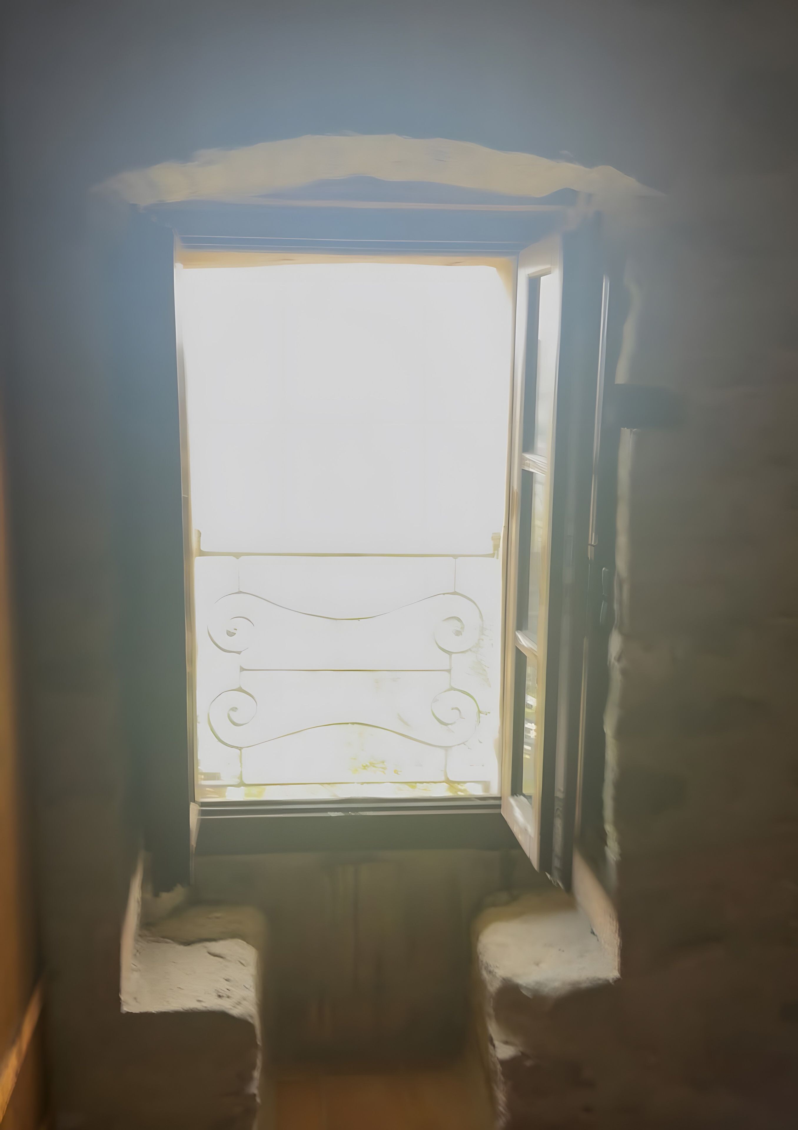 Ein schmales Fenster mit Metallgeländer, das zu einem kleinen Balkon führt.