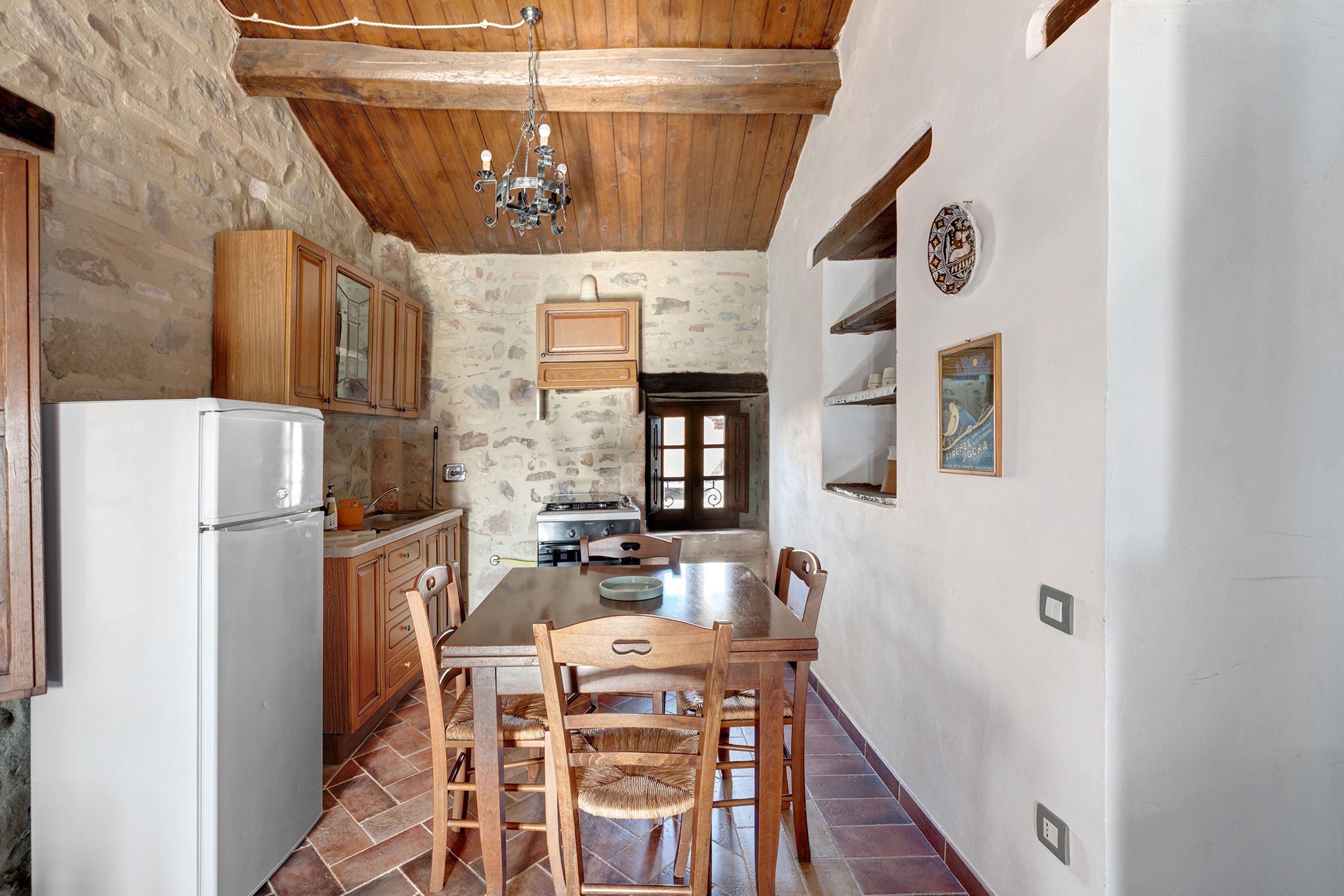 Una cocina rústica con armarios de madera, una mesa de comedor y una araña.