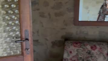 A room with a wooden door, a patterned wall, and a floral sofa.