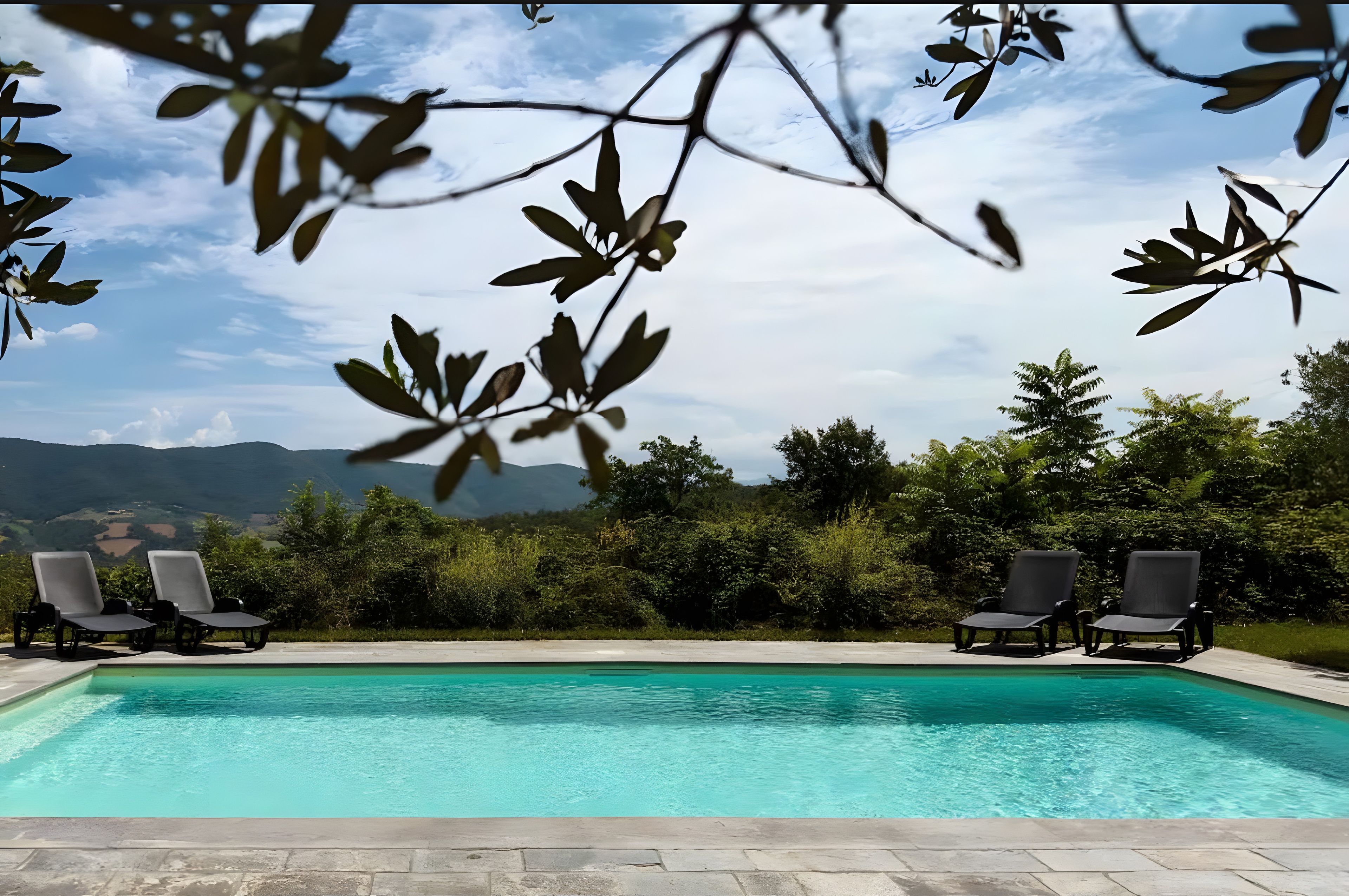 A swimming pool with lounge chairs and a view of mountains.